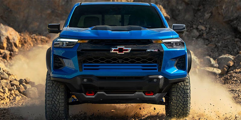 A front view of a blue 2025 Chevrolet Colorado driving in a rocky terrain